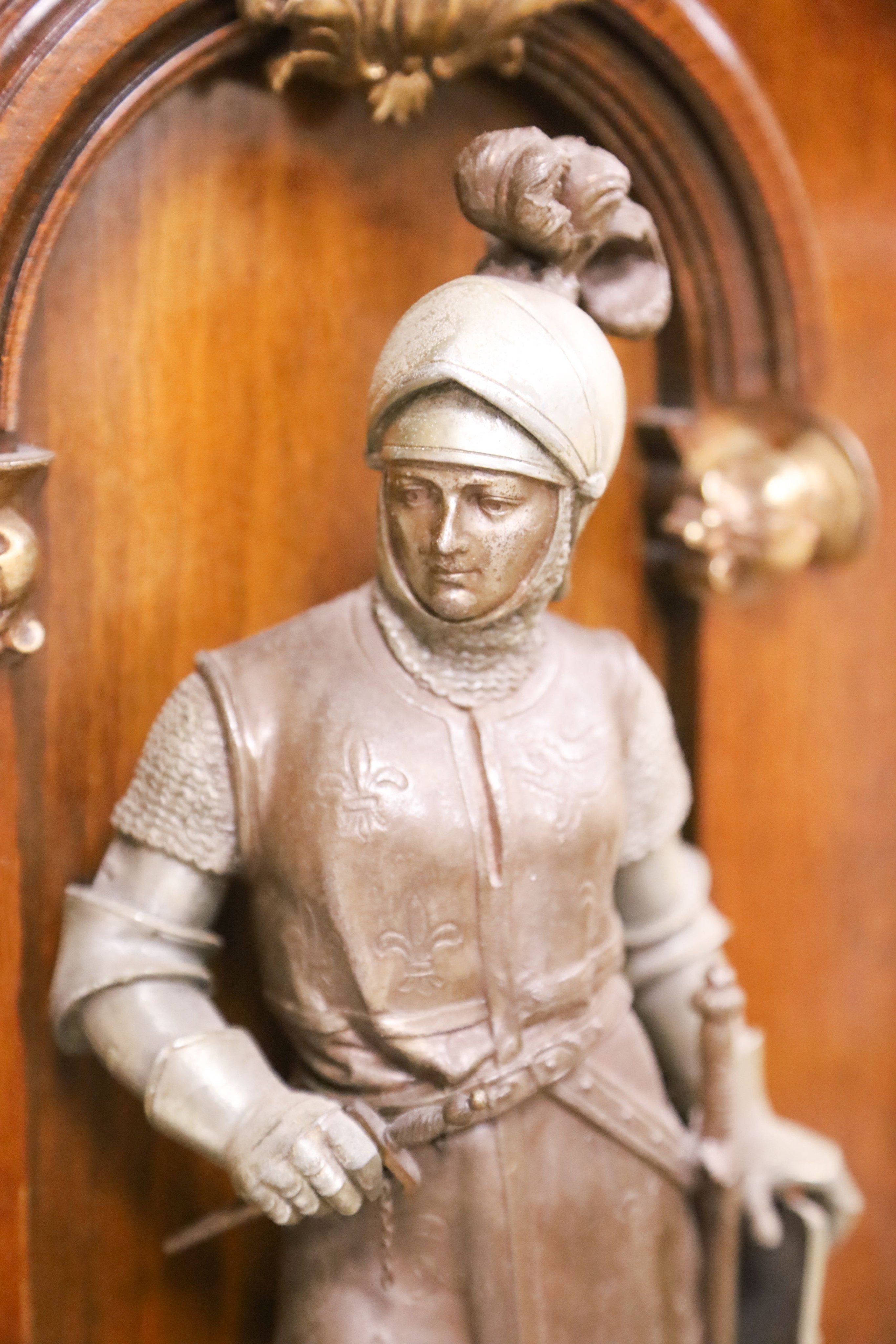 A pair of cast spelter figures of a medieval knight and a cavalier, each mounted on a mahogany niche